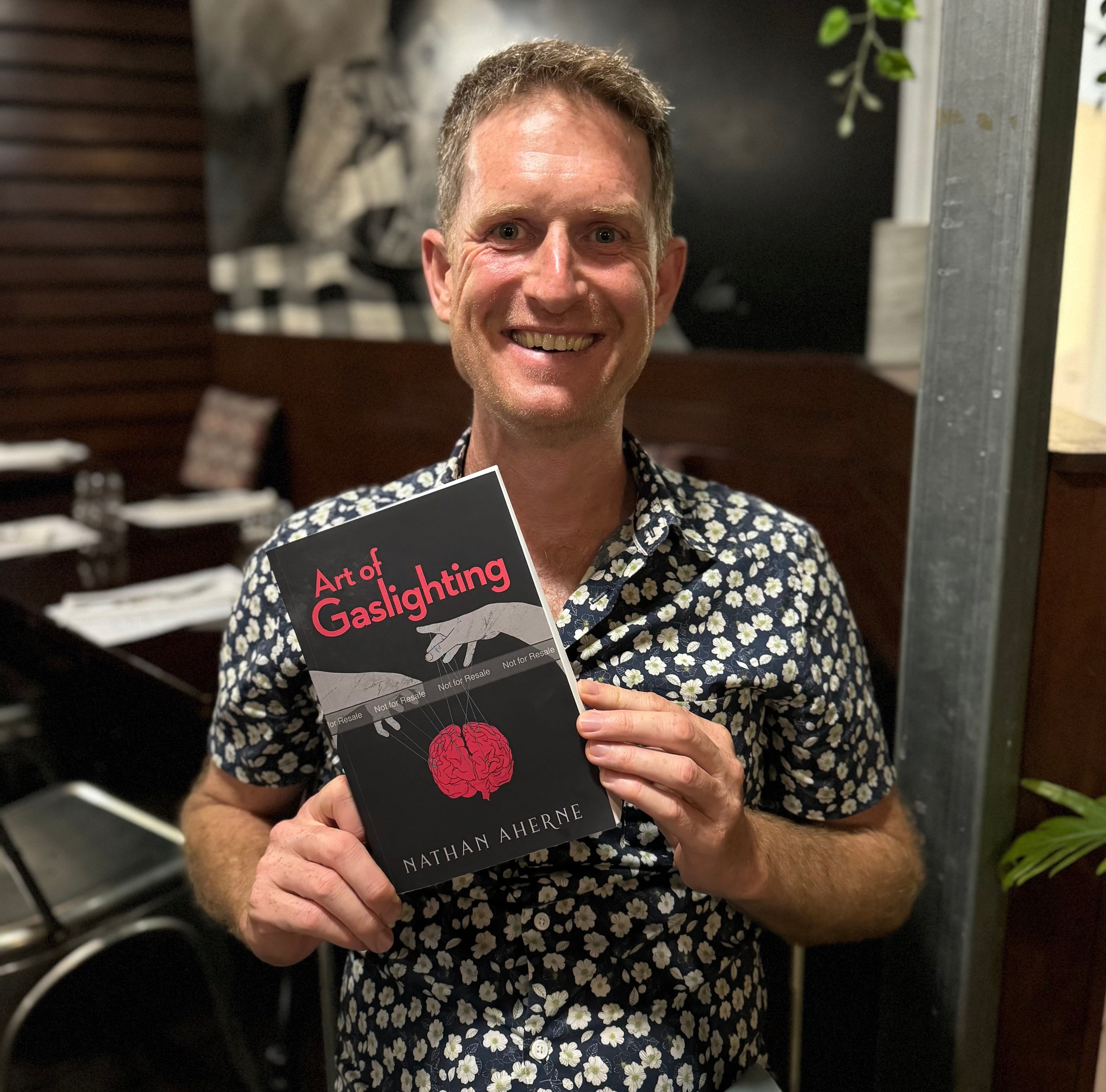 Nathan Aherne holding a proof copy of Art of Gaslighting